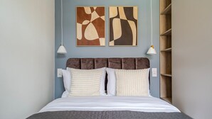 A bed with a brown headboard, white bedding, and a gray quilt. There are two wall-mounted light fixtures and abstract art above the bed. - Blueground | Nusle, view, furnished nr Vysehrad (PRG-70) (Prague)