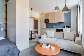 A compact living space with a sofa, a coffee table, a kitchen area, and a dining table. - Blueground | Nusle, view, furnished nr Vysehrad (PRG-70) (Prague)
