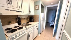 A compact kitchen with white cabinets, a stove, a sink, and a refrigerator. - Oceanfront, steps to the surf!
Boardwalk attractions and the airport nearby! (Myrtle Beach)