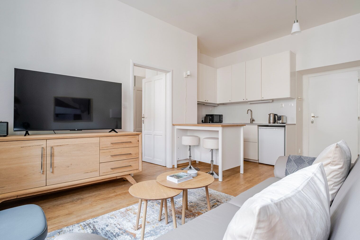 Un salon moderne avec un téléviseur à écran plat, un meuble en bois, une petite table ronde et un canapé.