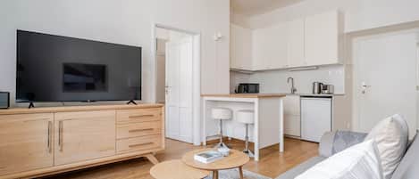 Un salon moderne avec un téléviseur à écran plat, un meuble en bois, une petite table ronde et un canapé.