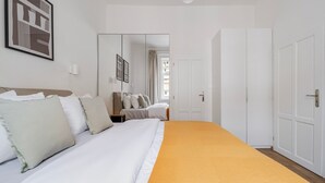 Ett hotellrum med en stor säng, en garderob, en spegel och en inramad tavla på väggen.