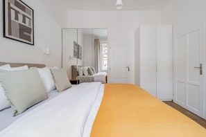 Ein Hotelzimmer mit einem großen Bett, einem Kleiderschrank, einem Spiegel und einem gerahmten Bild an der Wand.