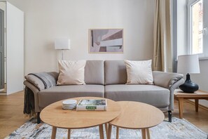 A modern living room with a sofa, two side tables, a lamp, and a book titled 'GREEN ARCHITECTURE'. - Blueground | Vinohrady, cafes, nr Riegrovy Sady (PRG-111) (Prague)