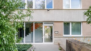 A building with a glass door entrance, a visible staircase, and a small garden area with plants. - Blueground | Nusle, city view, nr Vysehrad (PRG-108) (Prague)