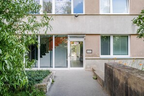 Ein Gebäude mit Glastür, sichtbarer Treppe und einem kleinen Garten mit Pflanzen.