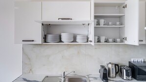 A kitchen with white cabinets, a marble backsplash, and a sink. - Blueground | Nusle, city view, nr Vysehrad (PRG-108) (Prague)