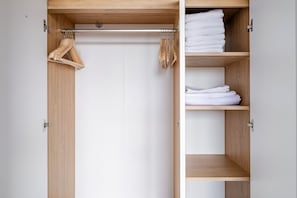 Ein Holzkleiderschrank mit Kleiderstange und Einlegeböden für gefaltete Kleidung.