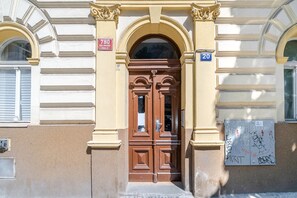 Une entrée d’immeuble dotée d’une double porte, d’une enseigne indiquant l’adresse et d’une plaque numérotée.