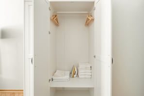 Um closet amplo e aberto, com uma barra para pendurar roupas e prateleiras para toalhas dobradas.