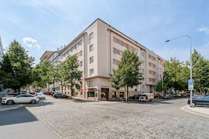 A multi-story hotel with a parking sign, cobblestone street, and trees. - Blueground | Vinohrady, view, nr Vysehrad (PRG-109) (Prague)