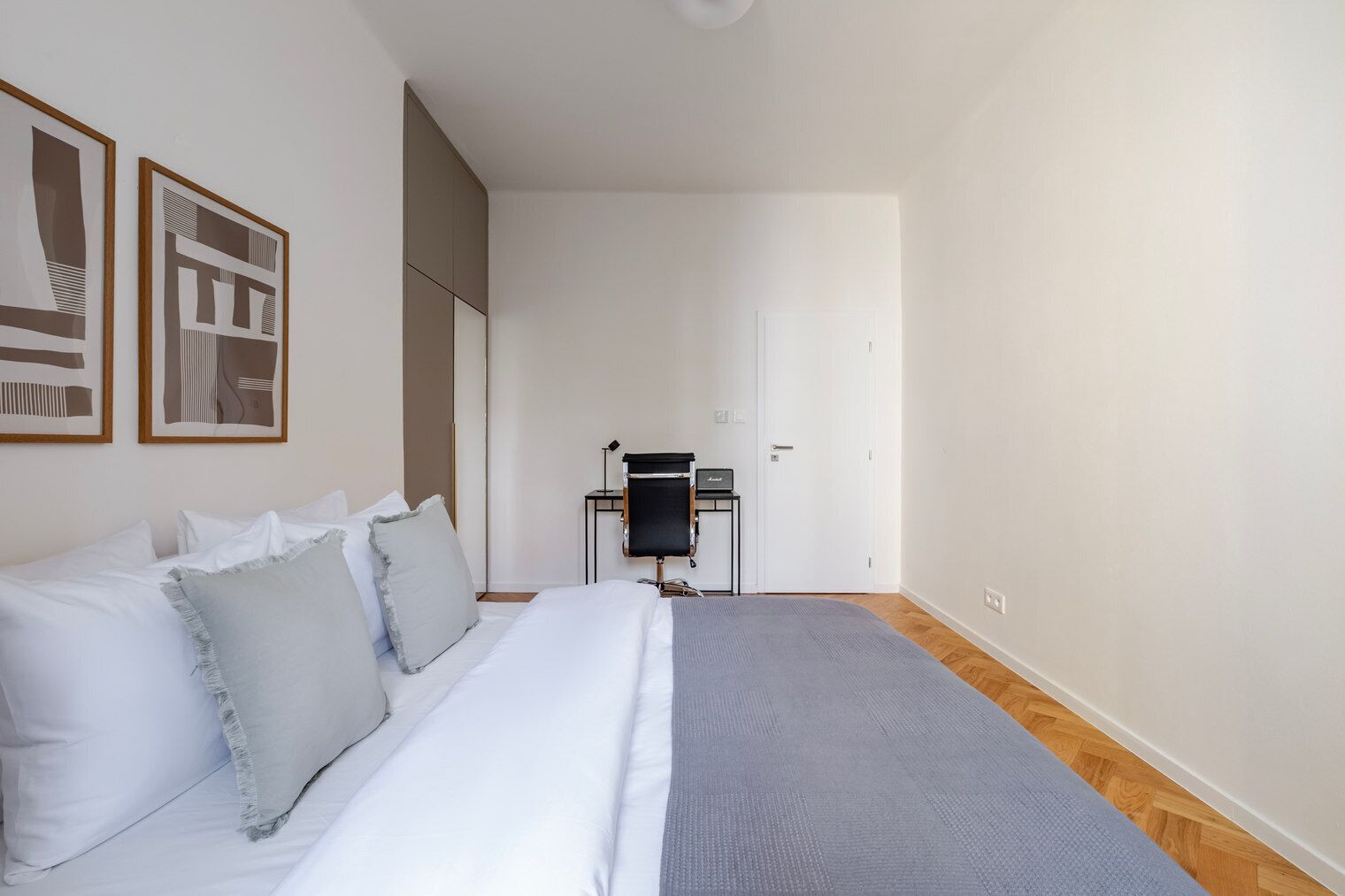 A bedroom with a bed, a desk, and a chair.