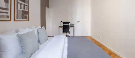 A bedroom with a bed, a desk, and a chair.