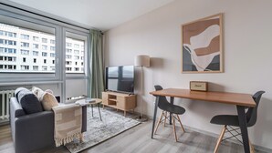 A modern living room with a sofa, a TV, a wooden table, and a lamp. - Blueground | Pankrác, view, spacious, near offices (PRG-113) (Prague)