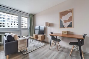 Ein modernes Wohnzimmer mit einer Couch, einem Fernseher, einem Holztisch und einer Lampe.