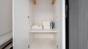 A white walk-in closet with shelves, a hanging rod, and a door. - Blueground | Pankrác, view, spacious, near offices (PRG-113) (Prague)