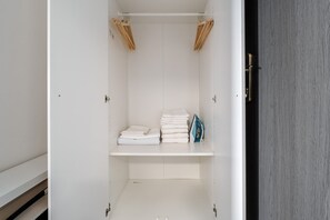 Ein begehbarer Kleiderschrank mit Regalen, einer Kleiderstange und einer Tür.