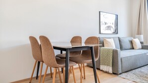 Ein modernes Wohnzimmer mit Esstisch und Stühlen, einem grauen Sofa und einem gerahmten Kunstwerk an der Wand.