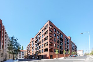 A modern multi-story building with a brick facade, large windows, and a flat roof. - Blueground | Žižkov, garden view, nr Vitkov (PRG-114) (Prague)