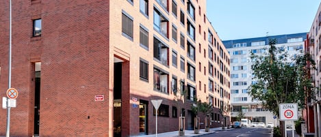 A multi-story building with a brick facade, a pedestrian crossing, and a speed limit sign.