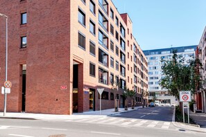 Ein mehrstöckiges Gebäude mit Backsteinfassade, einer Fußgängerampel und einem Geschwindigkeitsbegrenzungsschild.