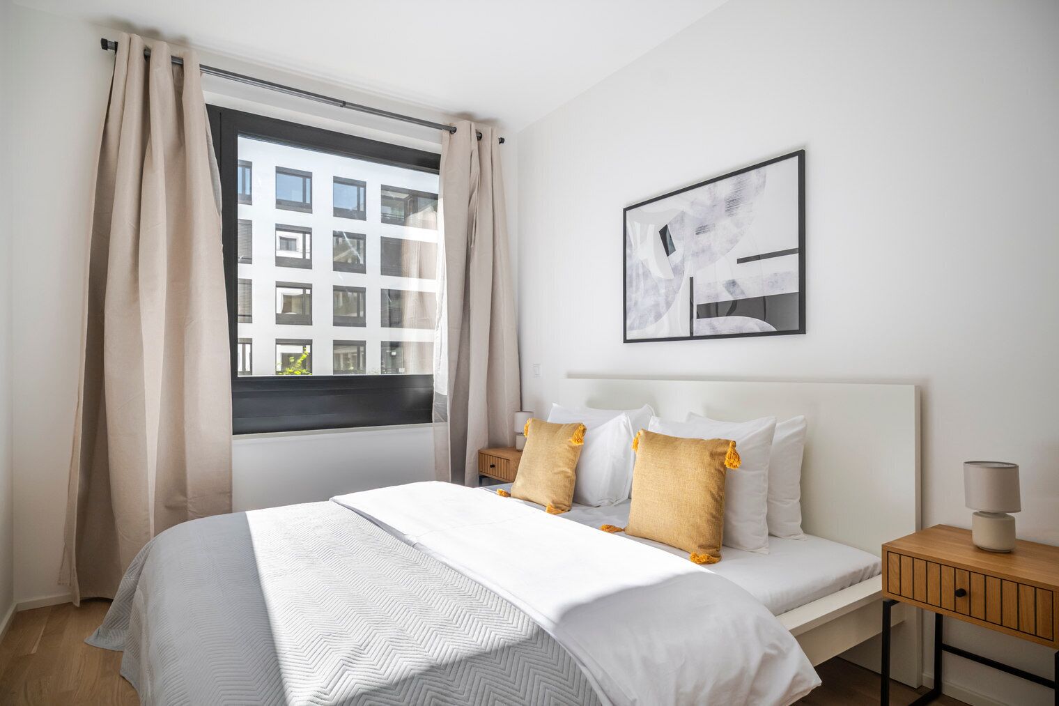A hotel room with a large bed, a bedside table with a lamp, and a window with curtains.