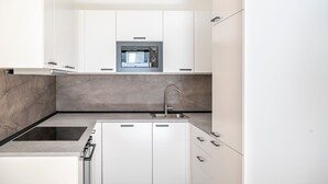 Een moderne keuken met witte kastjes, een inbouwoven en een roestvrijstalen spoelbak.