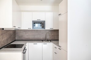 Eine moderne Küche mit weißen Schränken, einem eingebauten Backofen und einer Spüle aus Edelstahl.