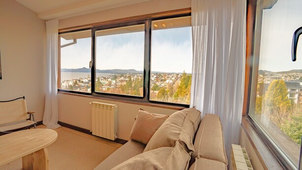 Una habitación con un ventanal grande, un radiador, un sofá y una silla.