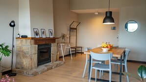Un comedor con una mesa de madera, sillas, un jarrón con flores y una chimenea.