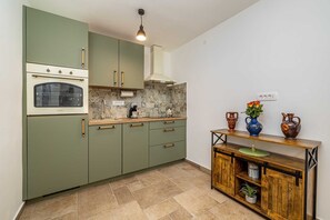 A compact kitchen with a built-in oven, a coffee maker, and a wooden sideboard with decorative items. - Holiday house SAN LEONARDO with private pool (Bajčići)