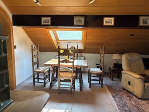 Uma área de jantar com mesa e cadeiras de madeira, um claraboia e um sofá.