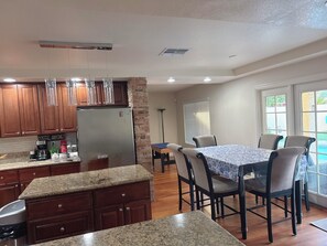 A kitchen with granite countertops, wooden cabinets, and a stainless steel refrigerator. - Modern 4BR Pool & Spa Oasis • Sleeps 10 (Las Vegas)