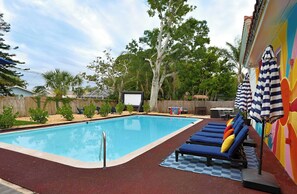 A swimming pool with lounge chairs and a covered area with umbrellas. - Game Room, Pool & Fire Pit Near Madeira Beach (Seminole)