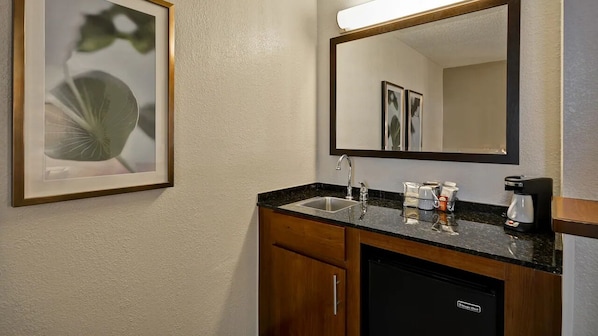 Een badkamer met een wastafel, spiegel en een foto in een lijst aan de muur.