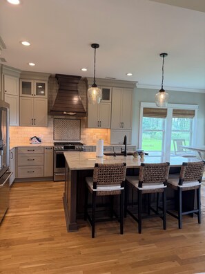 A modern kitchen with wooden cabinets, a central island, and pendant lighting. - MarshMellow -Peaceful Knott's Island Waterfront Retreat (knotts island)