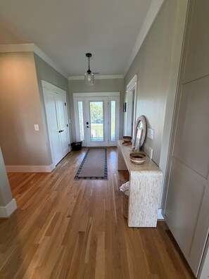 A hallway with wooden flooring, a ceiling fan, and a door leading to a backyard.