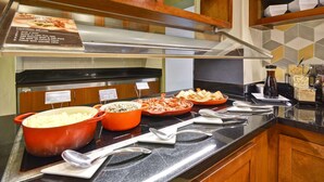 Un buffet avec des plats clairement identifiés, une hotte en acier inoxydable et des meubles de rangement en bois.