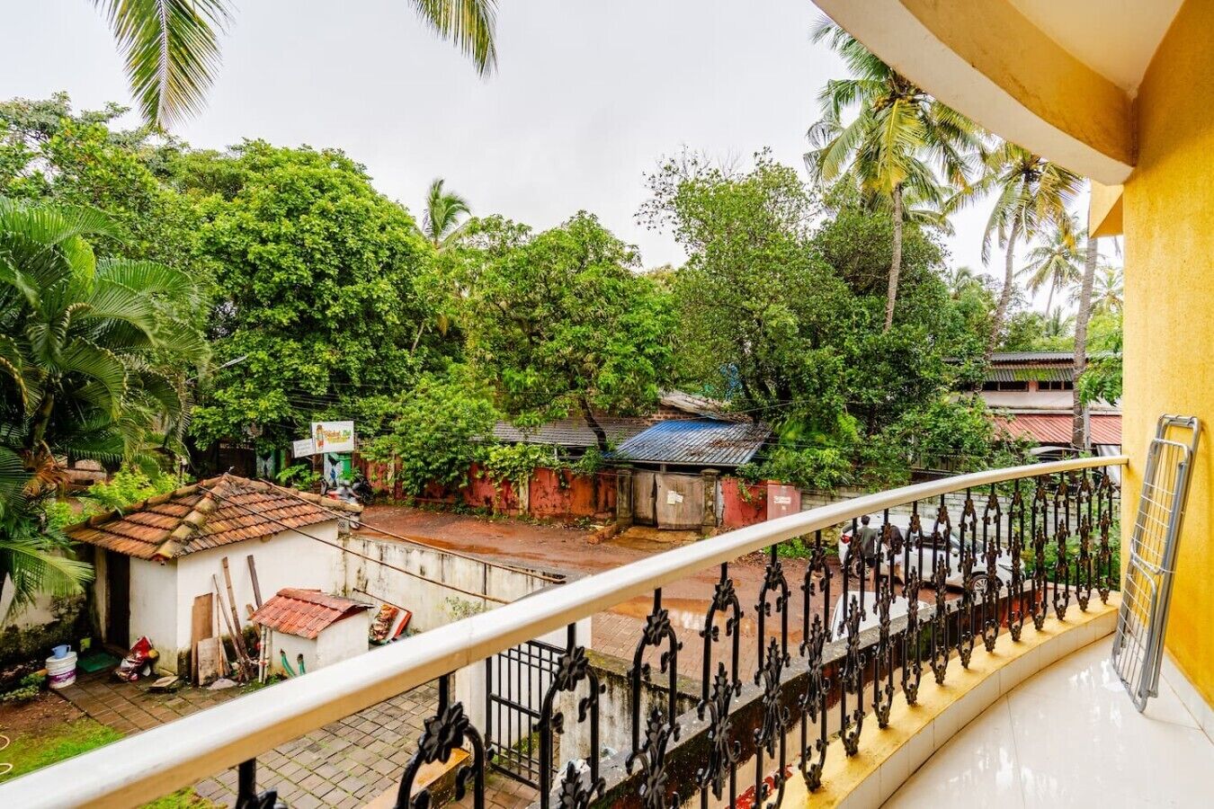 Ein Balkon mit Blick auf ein kleines Haus, einen Garten und eine Palme.