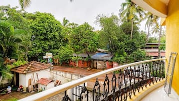 Ein Balkon mit Blick auf ein kleines Haus, einen Garten und eine Palme.