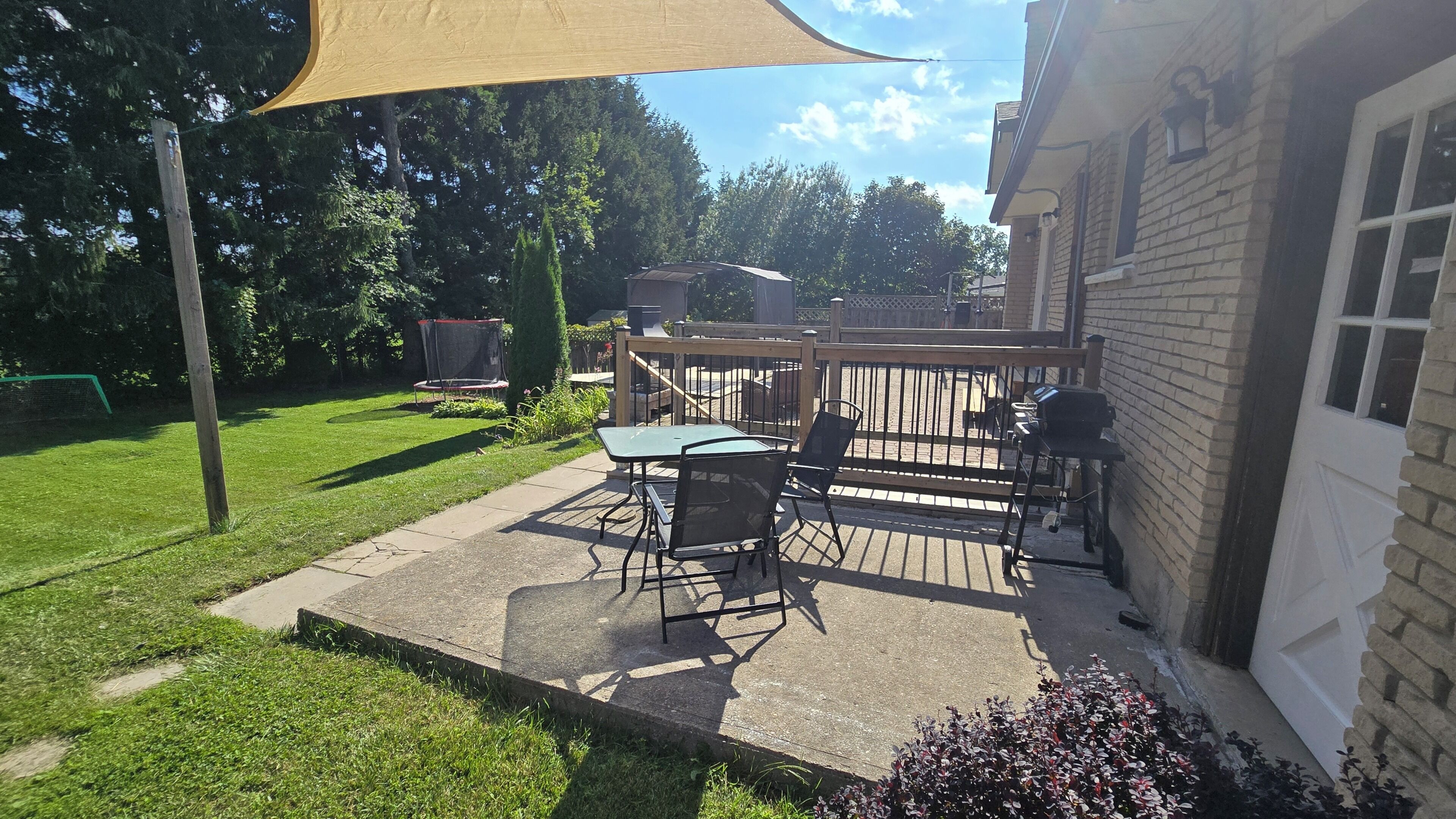 Un patio con mesa y sillas, una parrilla y una terraza de madera.
