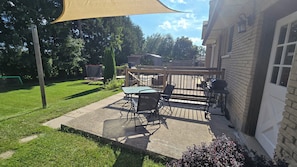 A patio with a table and chairs, a barbecue grill, and a wooden deck.