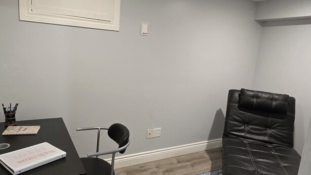 A room with a desk, chair, and a black leather couch. - Modern comfort meets unique two level split suite. Family size and Pet Friendly (Cobourg)