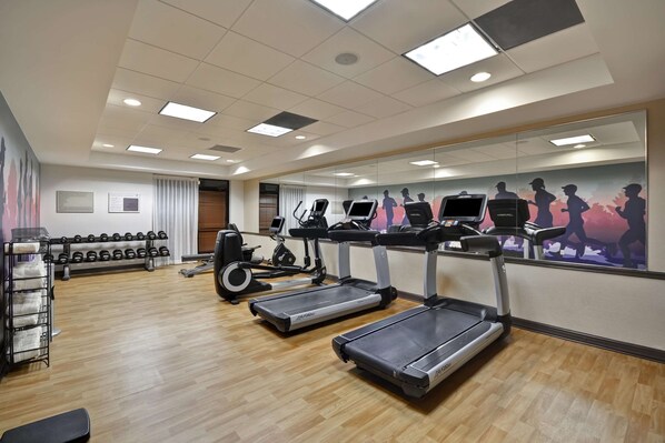 A gym with treadmills, dumbbells, and exercise equipment.