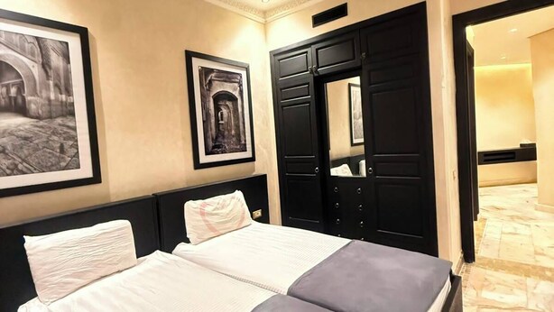 A hotel room with a double bed, a large mirror, and two framed pictures on the wall. - BELLA Palmeraie Apartment (Marrakech)