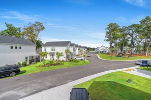 A residential street with single-family homes, a clear sky, and a parked car. - Private Oasis • HotTub & Arcade! (North Myrtle Beach)