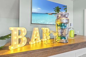 A bar setup with illuminated letters spelling 'BAR', a cocktail glass, a blender, and a bottle of liquor on a wooden surface. - Private Oasis • HotTub & Arcade! (North Myrtle Beach)