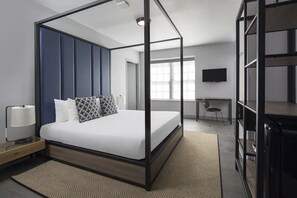 Ein modernes Schlafzimmer mit einem Himmelbett, einem Schreibtisch und einem Fernseher.