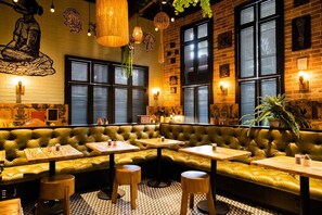 A cozy restaurant interior with a green leather booth seating area, wooden tables, hanging pendant lights, and brick walls. - Rendale | Junior Suite | Near South Beach | Oaxacan Dining | 2 Units (Miami Beach)