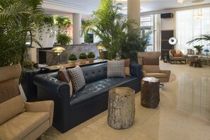 A modern lobby with a dark blue sofa, multiple chairs, a coffee table, and a variety of potted plants. - Rendale | Junior Suite | Near South Beach | Oaxacan Dining | 2 Units (Miami Beach)